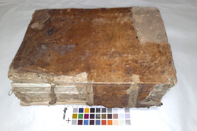 Volume con coperta in pergamena rigida strappata e attao fungino prima del restauro