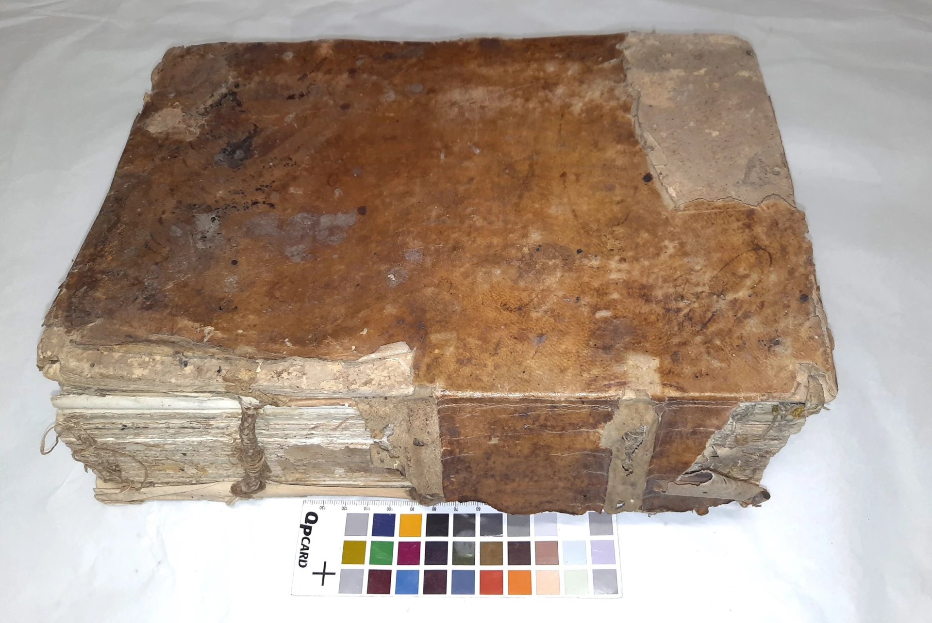  Volume con coperta in pergamena rigida strappata e attacco fungino prima del restauro